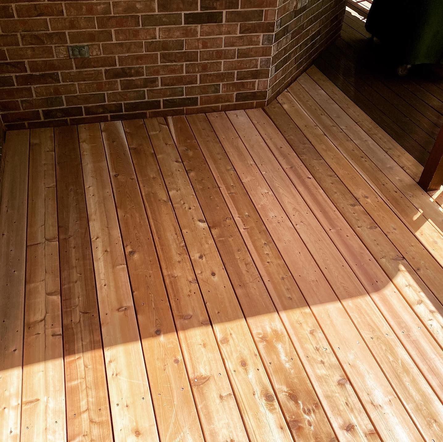 A wooden deck with a brick wall in the background