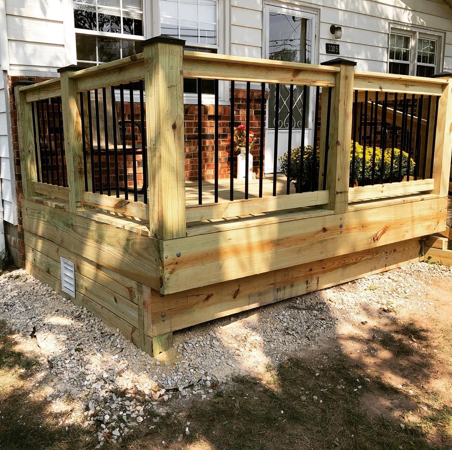 A wooden deck with a black railing is sitting in front of a house.