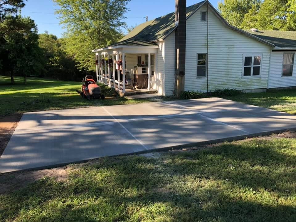 A white house with a concrete driveway in front of it.