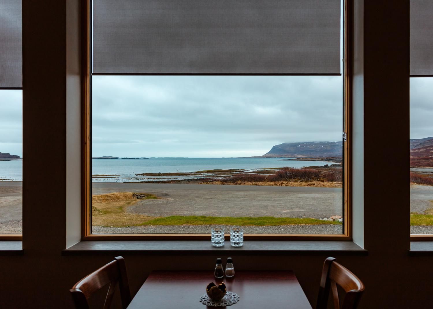 Table set for two, framed view of ocean, cloudy sky.