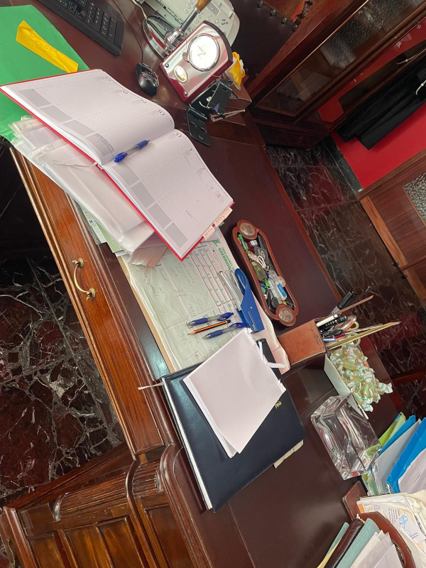 Una scrivania con documenti e un orologio sopra