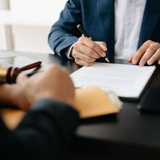 Un uomo in giacca e cravatta sta scrivendo su un pezzo di carta con una penna.