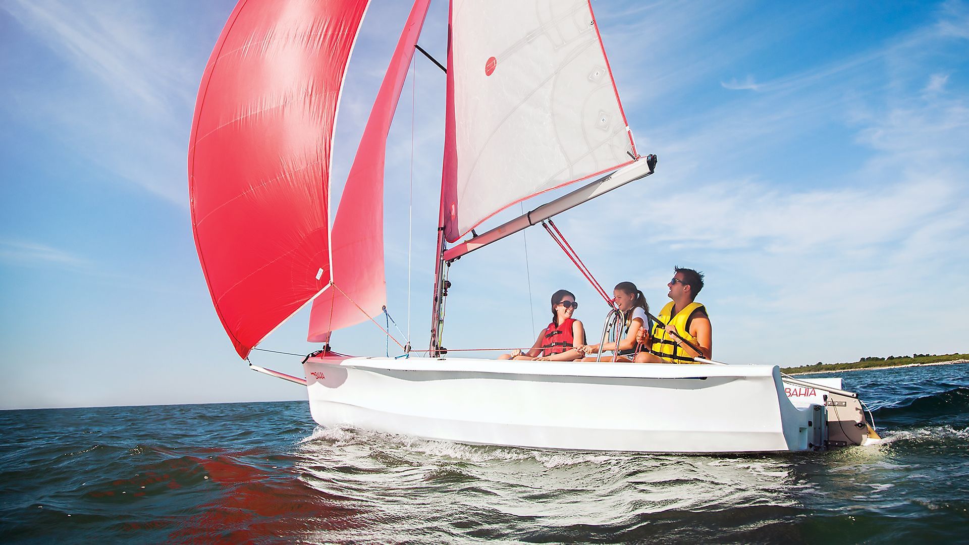 A group of people are sailing on a small sailboat in the ocean.
