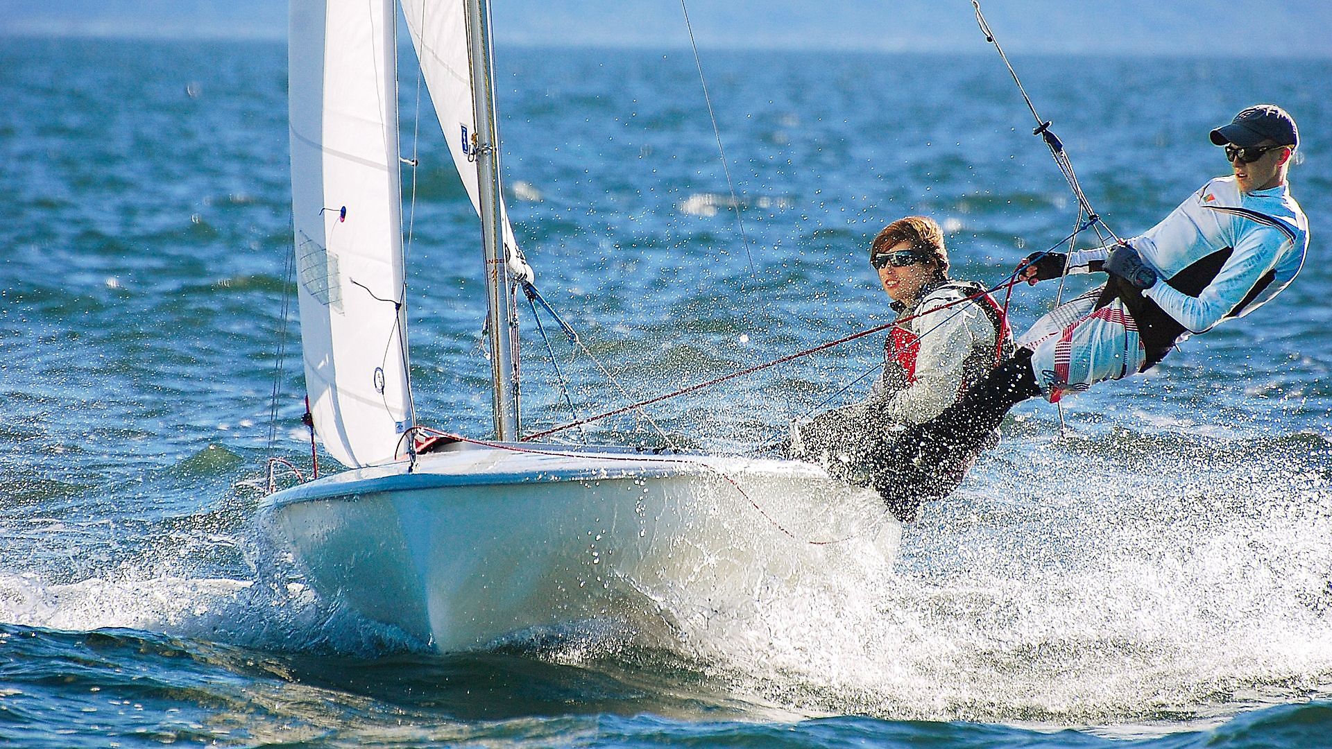 Two people are sailing a small boat in the ocean.