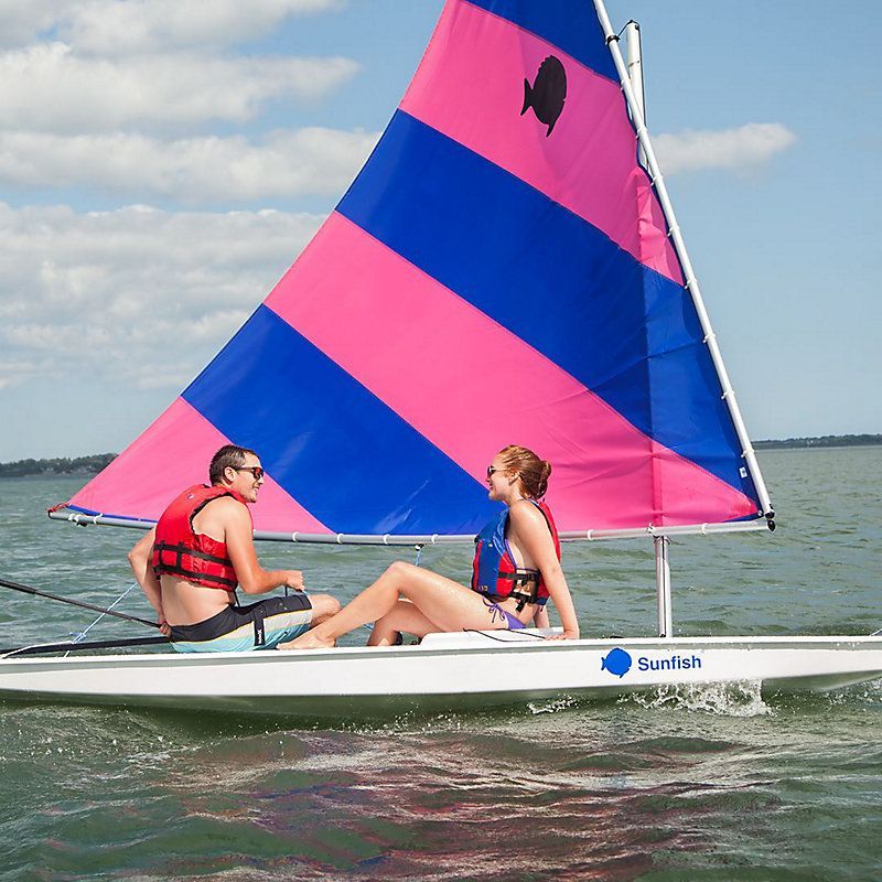 Two people on a sailboat that says sunfish on the side