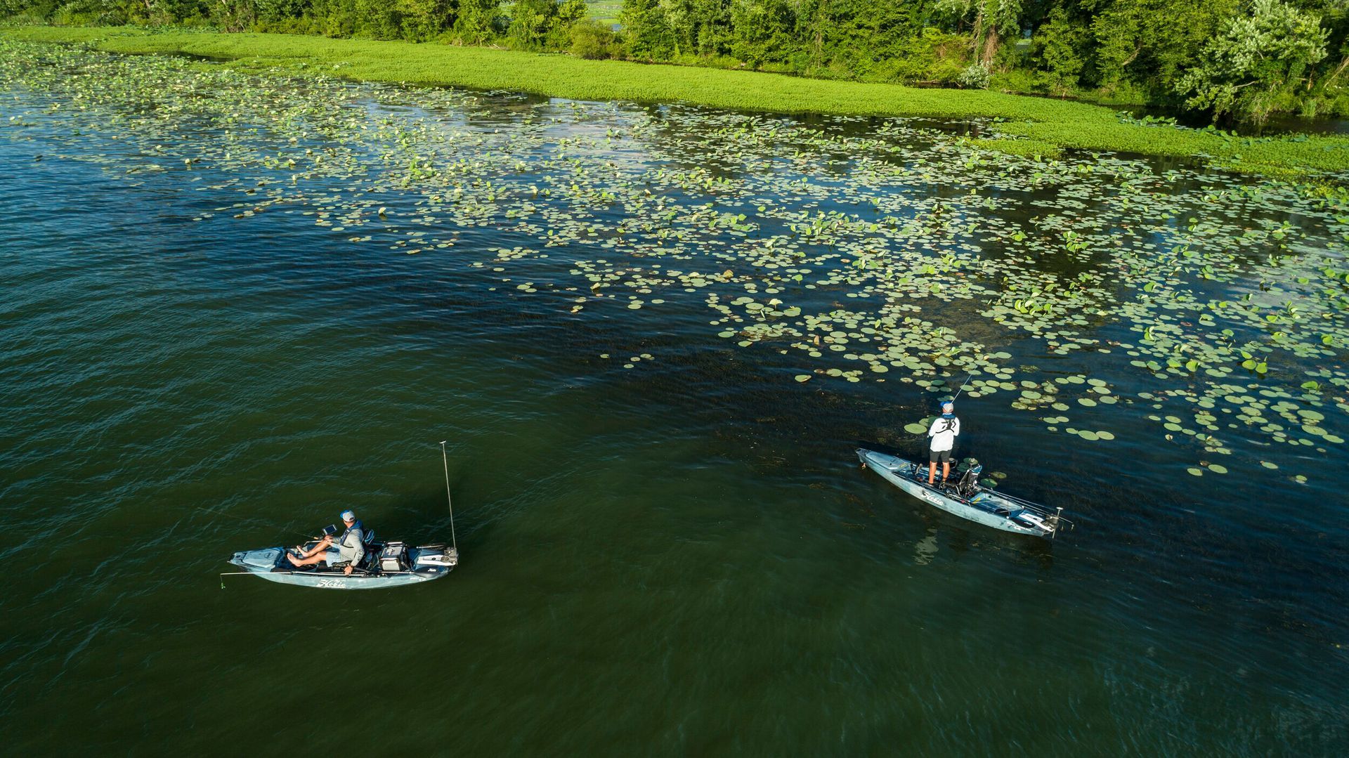 An aerial view of two people fishing in boats on a lake.