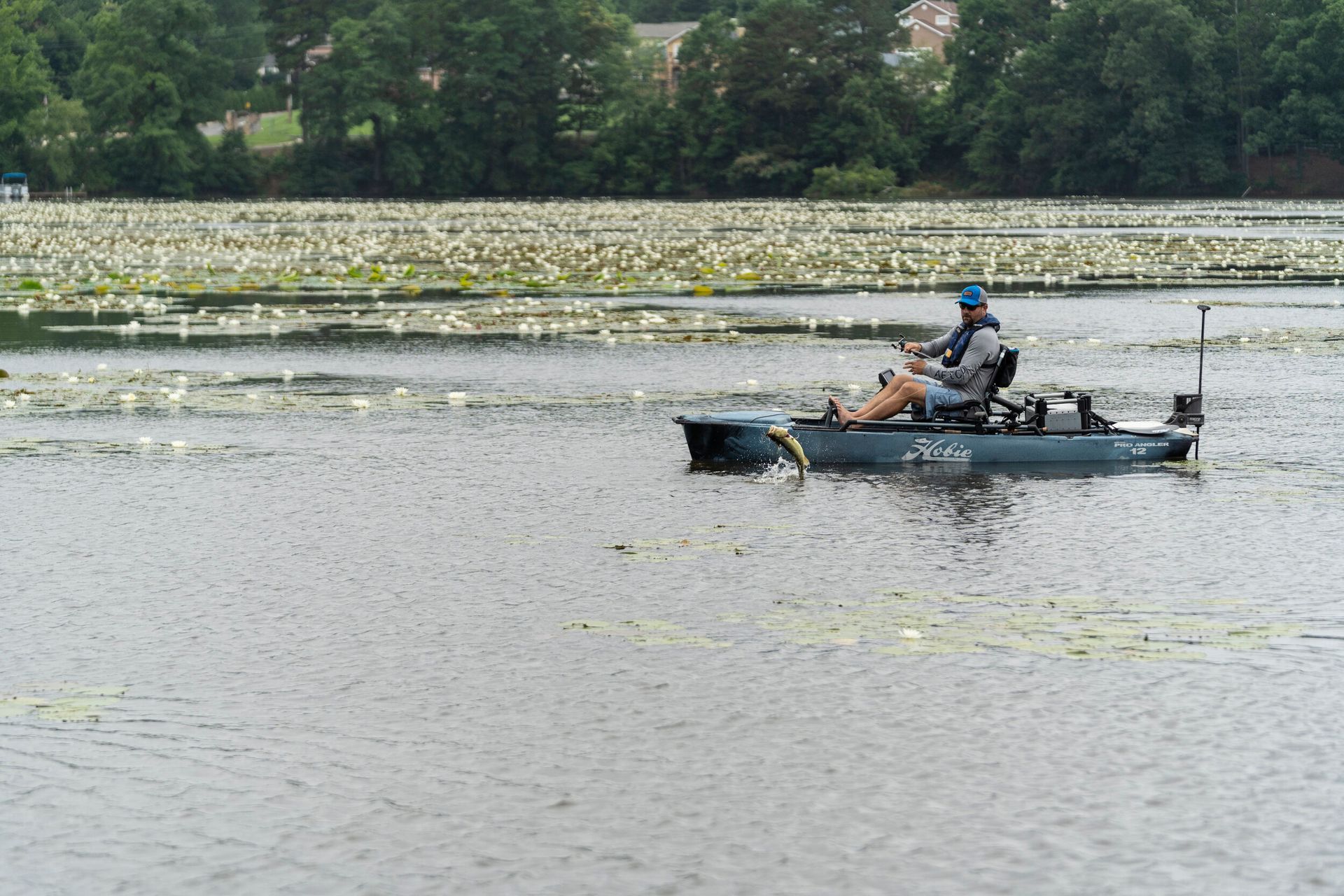 A man is fishing in a kayak on a lake.