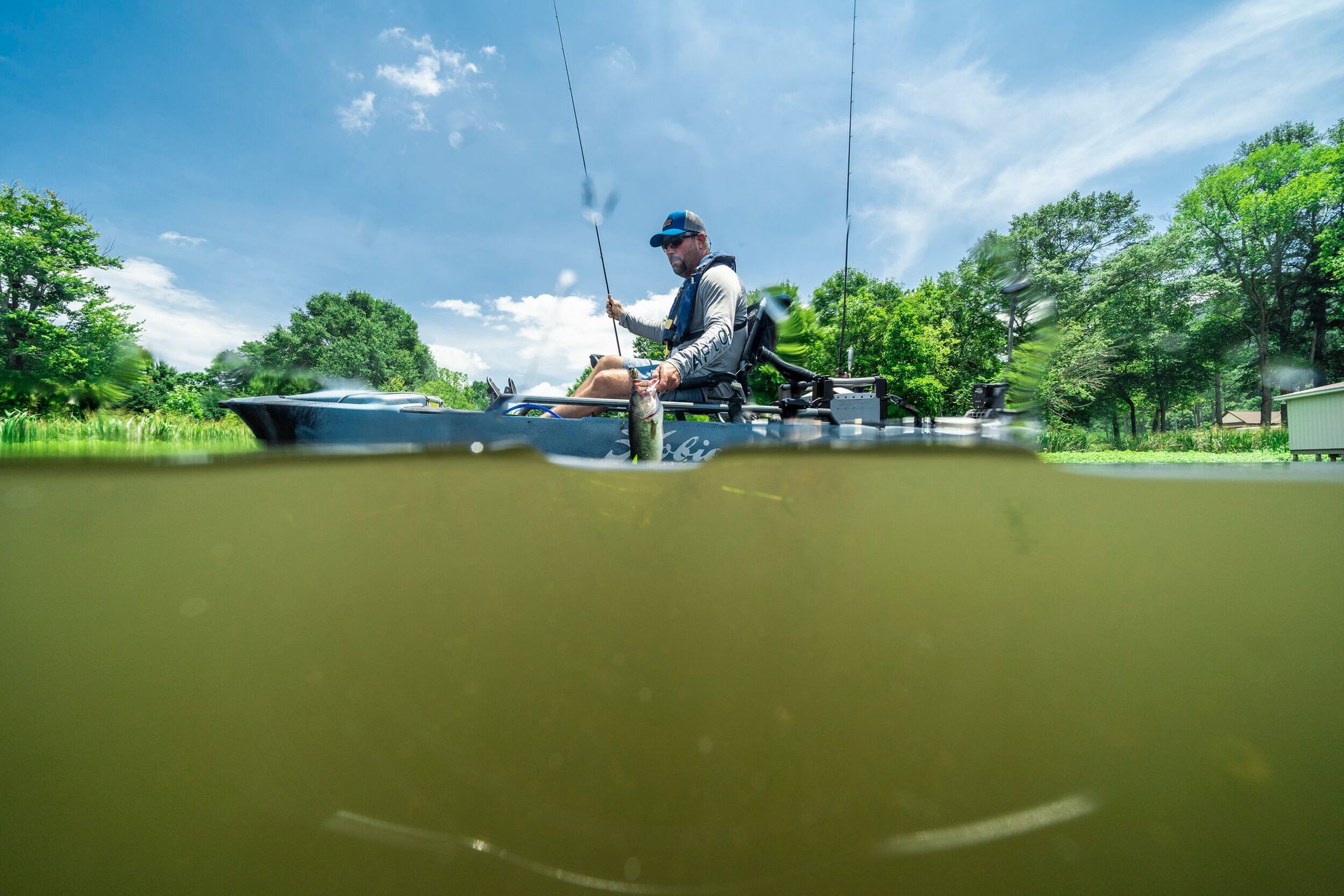 A man is fishing from a boat in a lake.
