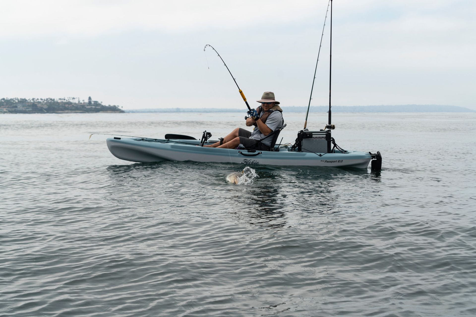 A man is fishing from a kayak in the ocean.