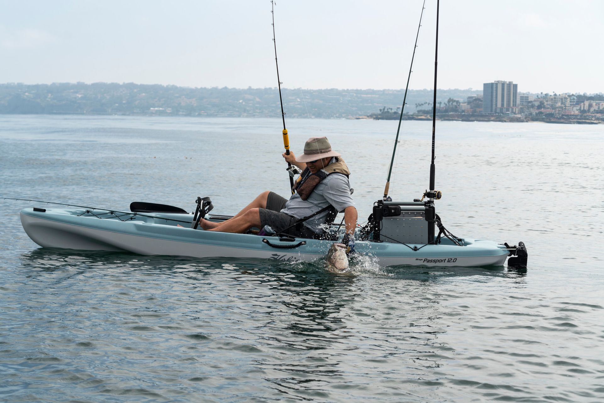 A man is fishing in a kayak on a lake.