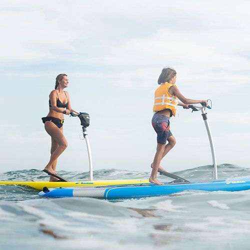 A woman and a boy are riding a paddle board in the ocean.