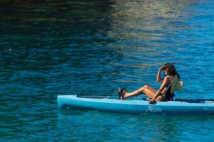 A woman is sitting in a blue kayak in the water.