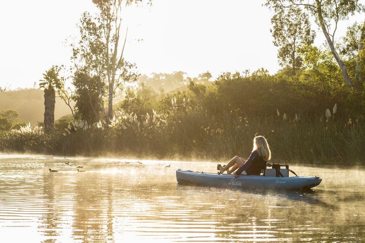 A woman is sitting in a kayak on a lake.