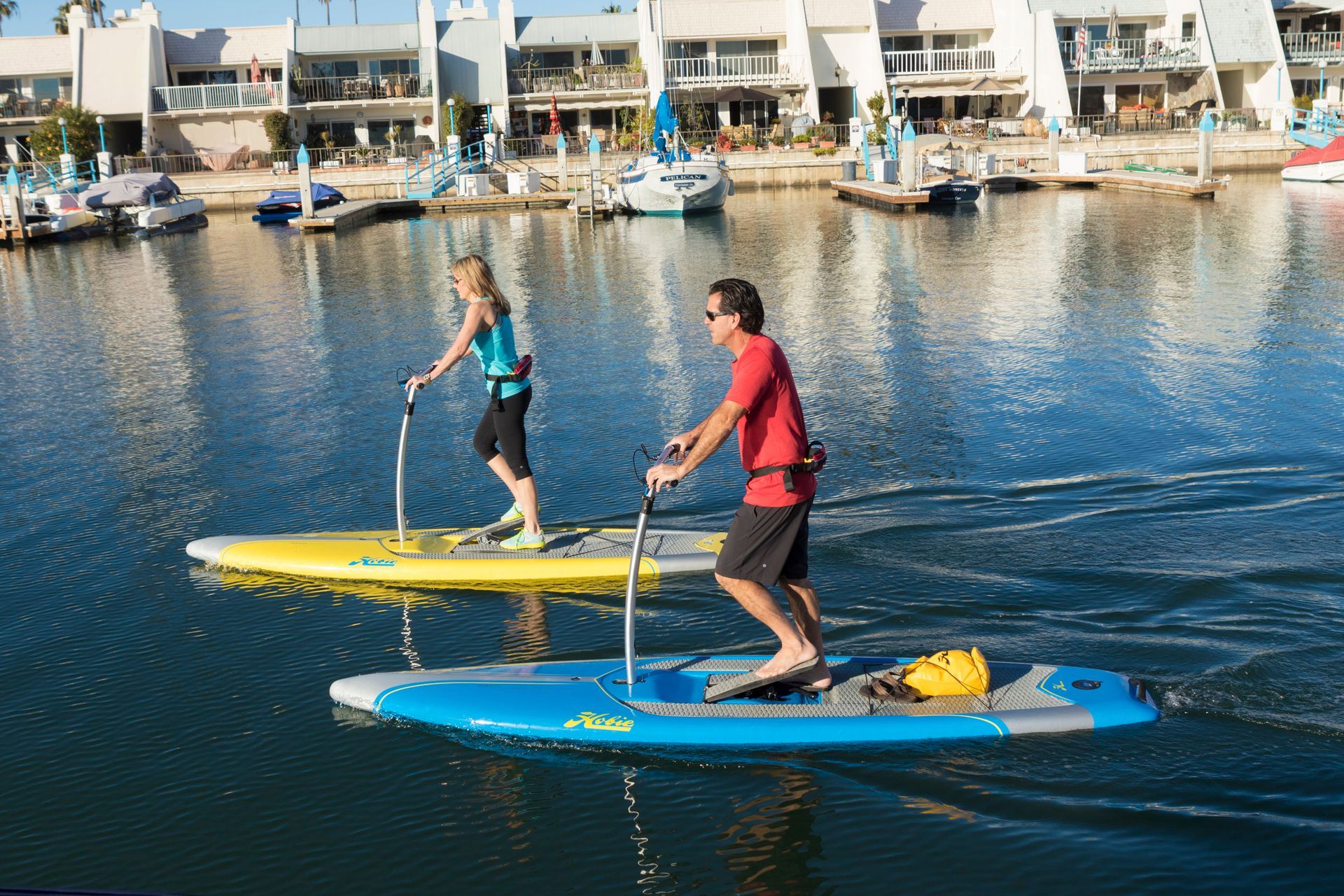 A man and a woman are riding paddle boards in the water.
