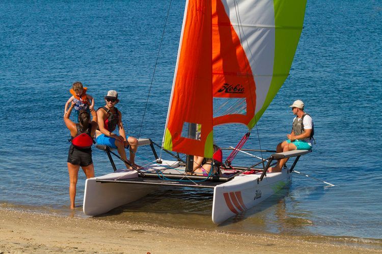 A group of people are sitting on a sailboat on the beach.