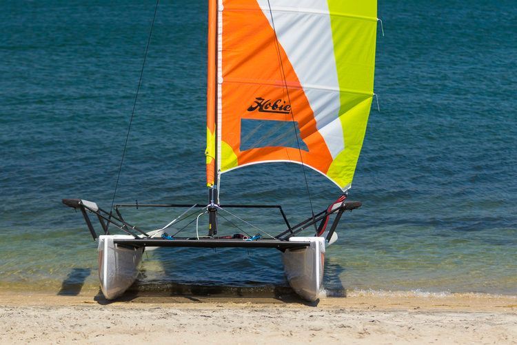 A sailboat is sitting on the beach near the water
