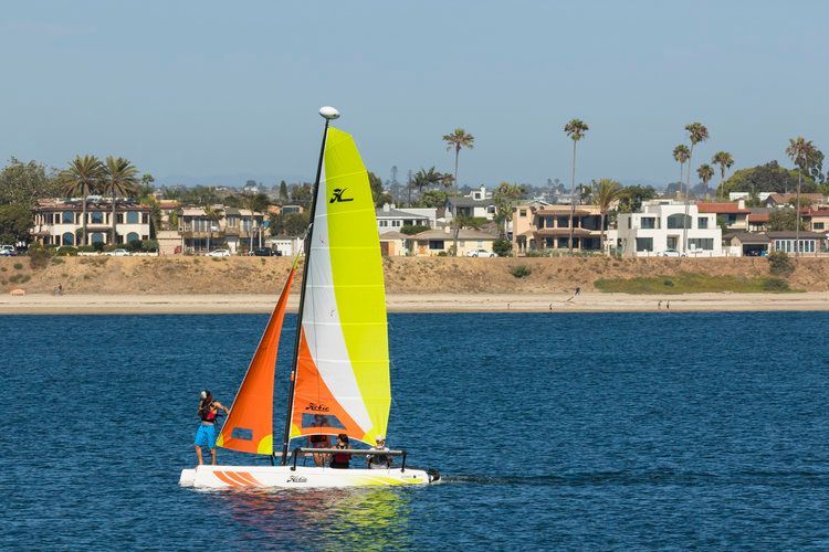 A sailboat with a yellow sail is floating on a body of water.