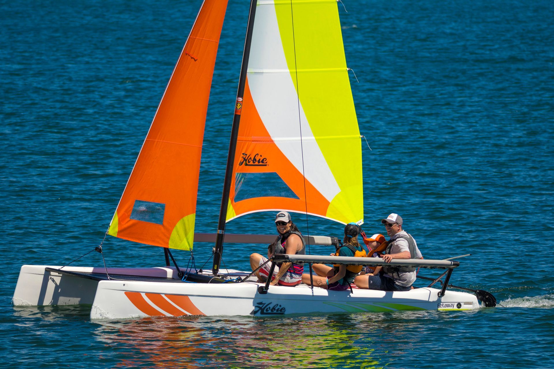 A group of people are sailing a sailboat in the water.