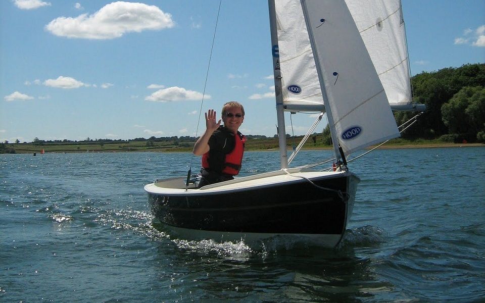 A man is sailing a small boat on a lake