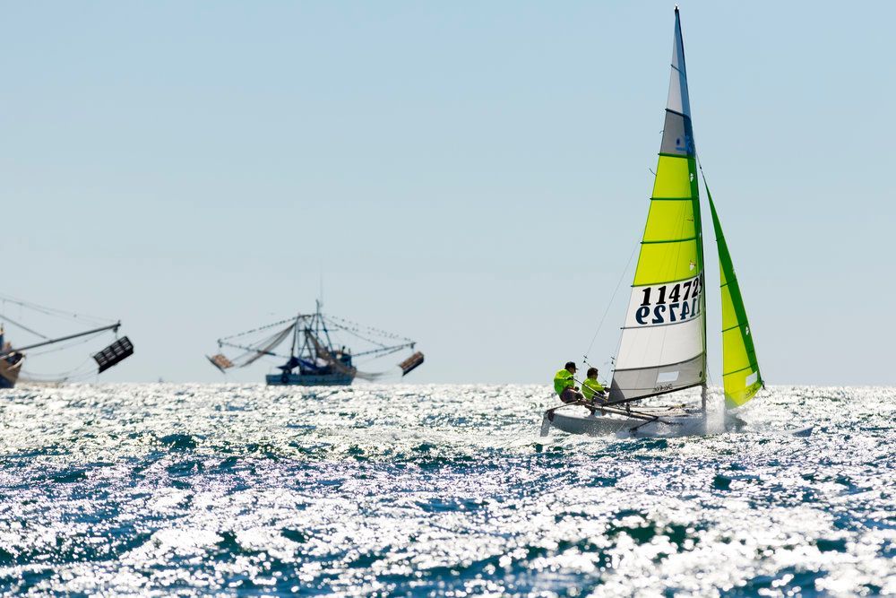A sailboat with a green sail is floating on top of a body of water.