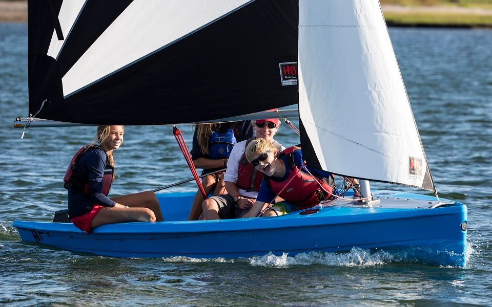 A group of people are sailing a small blue boat on a lake.