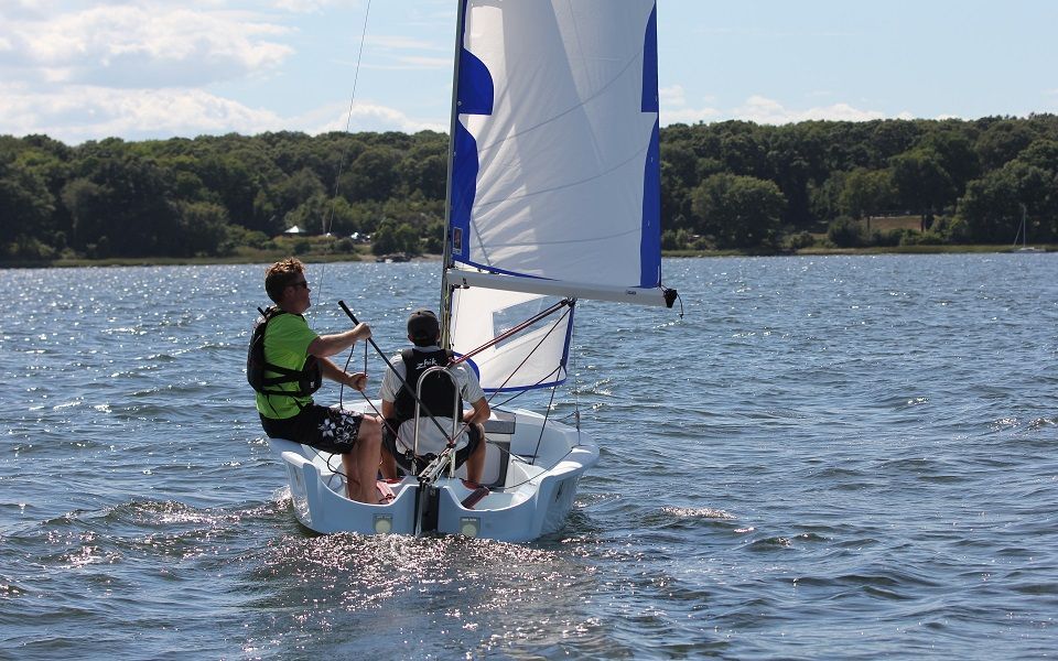 Two people are sailing a small boat on a lake