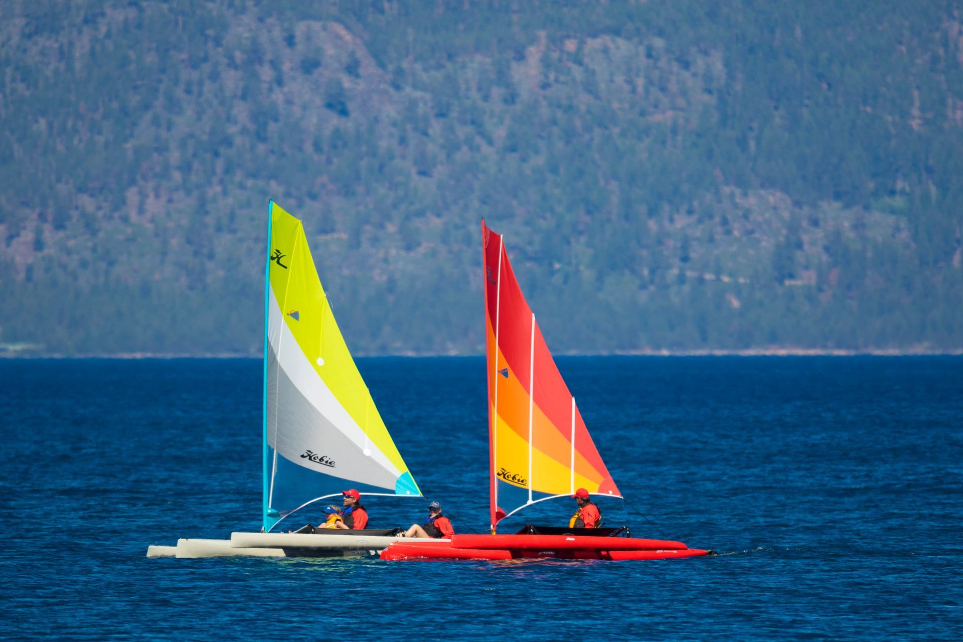 Two people are sailing boats in the ocean.
