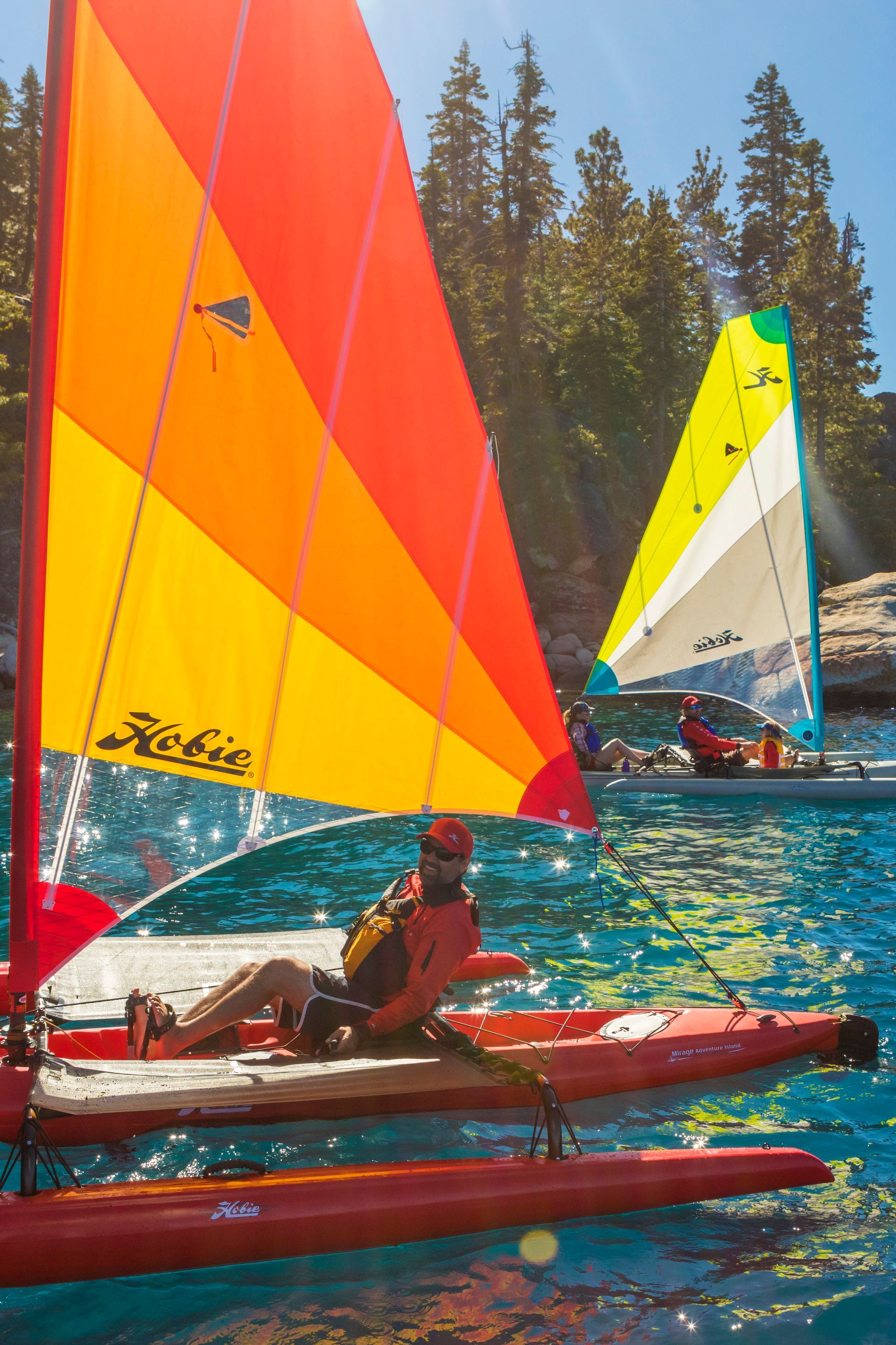A man is sitting on a sailboat in the water.