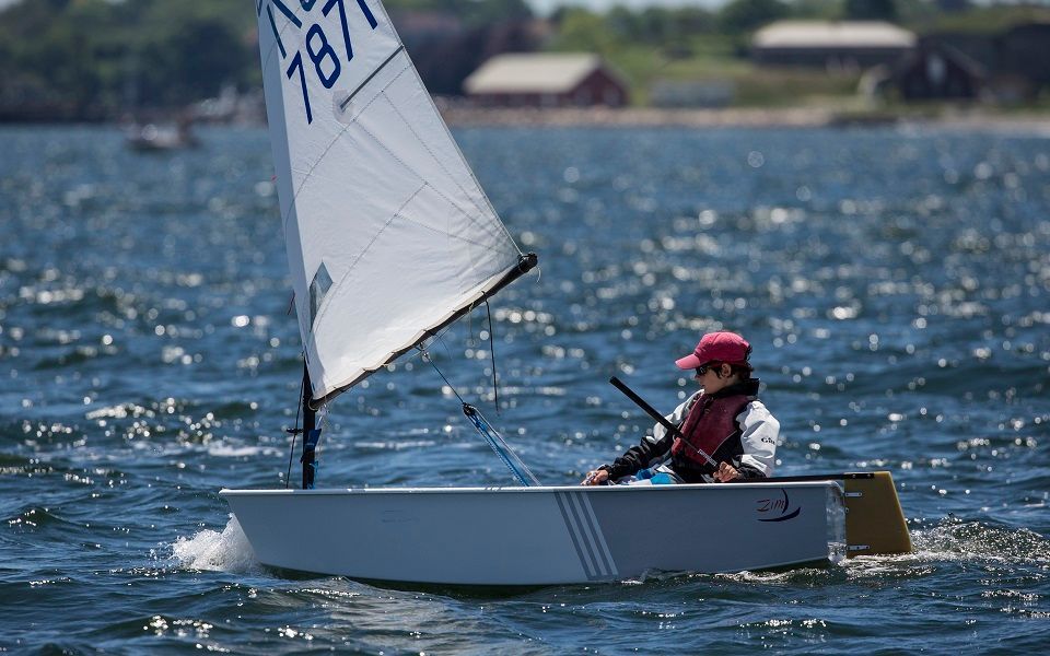 A person is riding a small sailboat in the water.