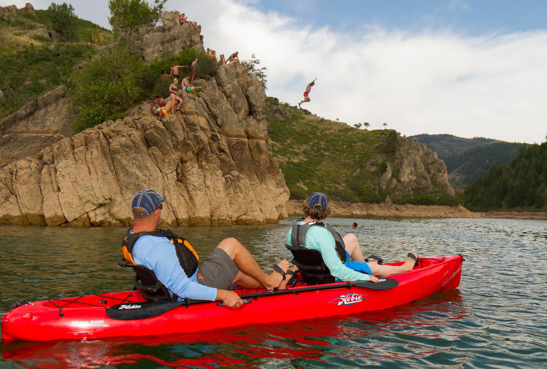 A man and a woman are in a red kayak on a lake