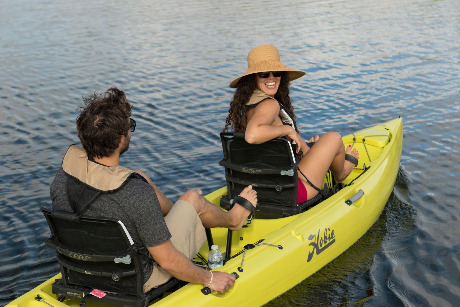 A man and a woman are sitting in a yellow kayak on a lake.
