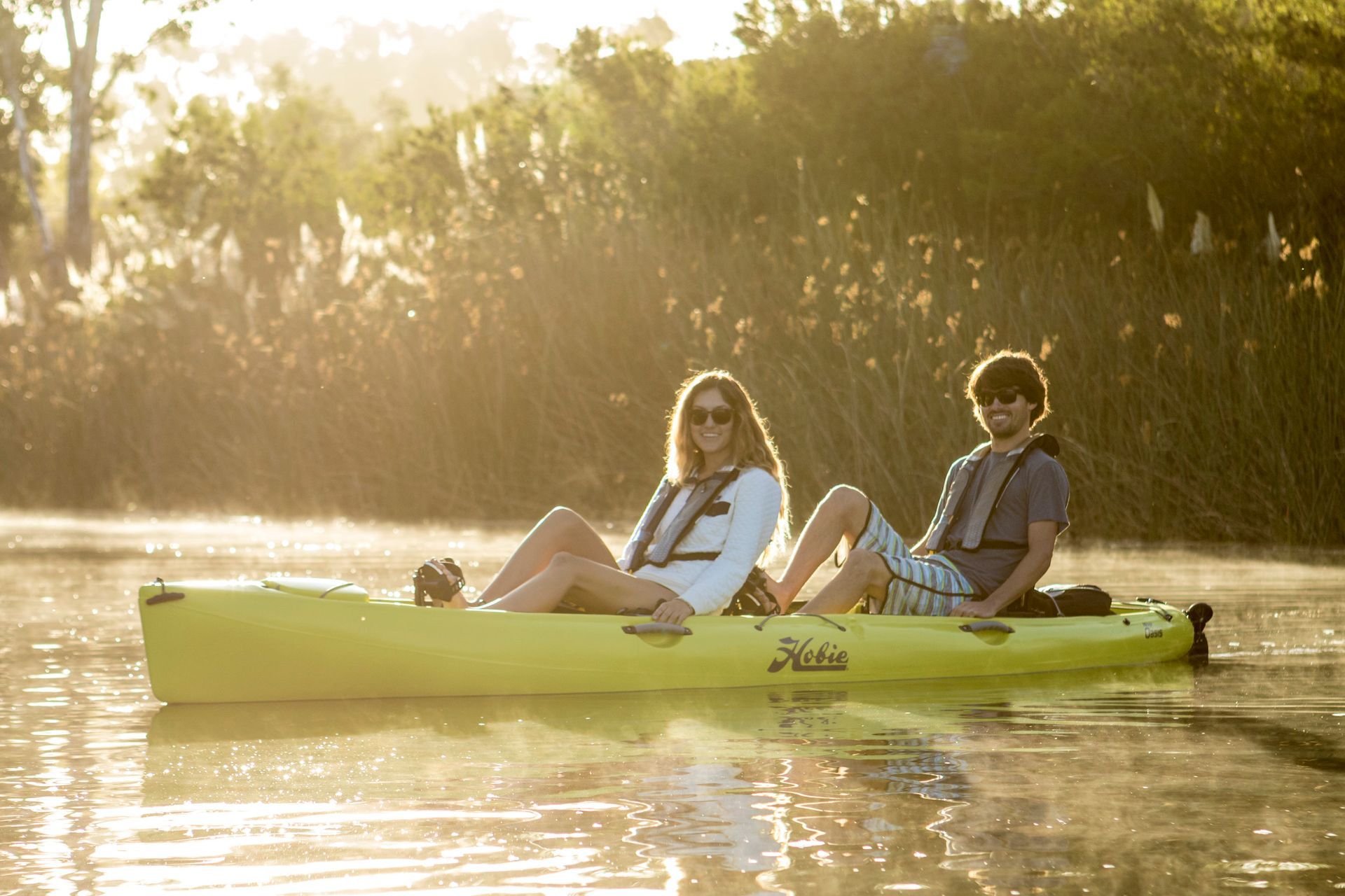 A man and a woman are sitting in a yellow kayak on a river.