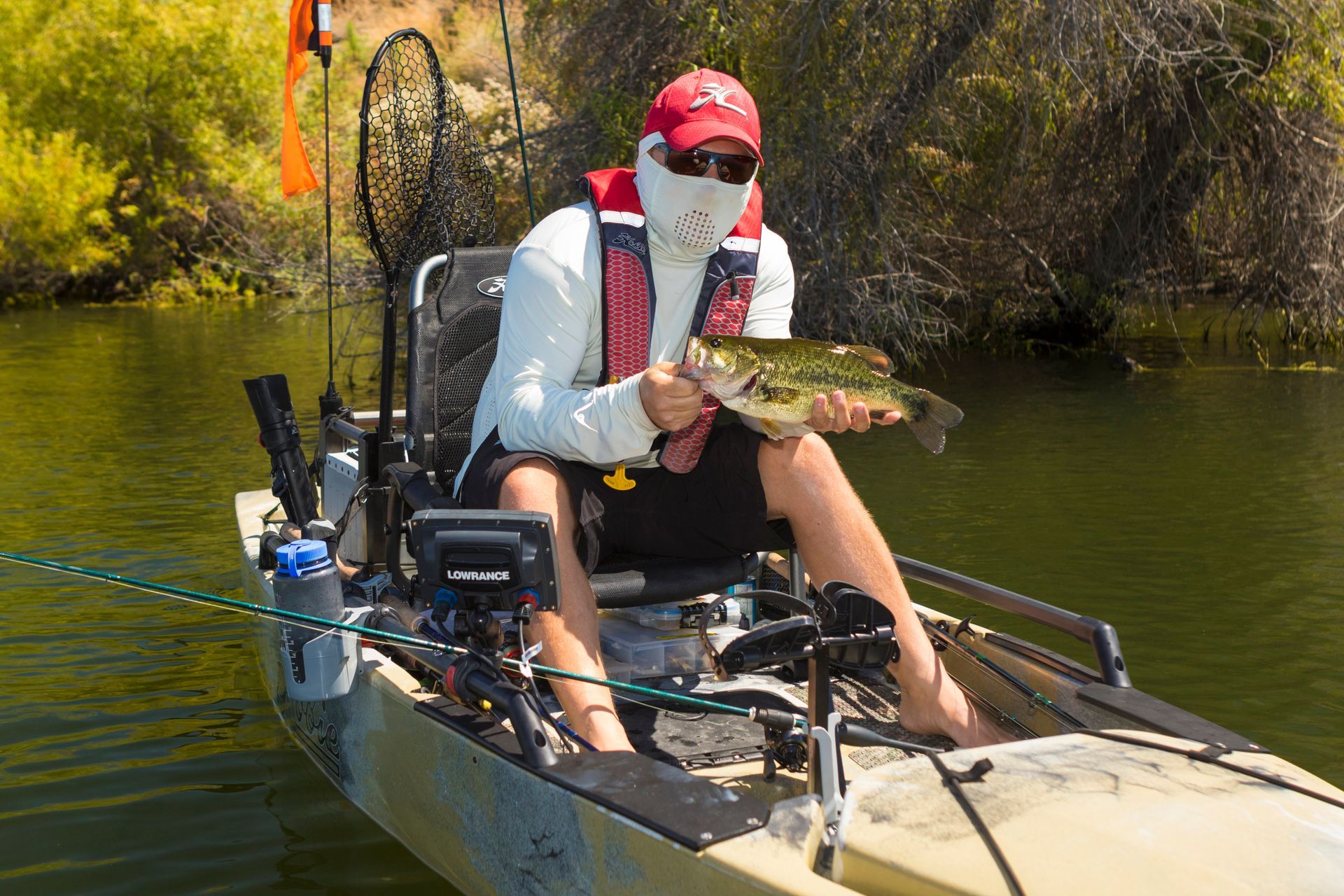 A man is sitting in a kayak holding a fish.