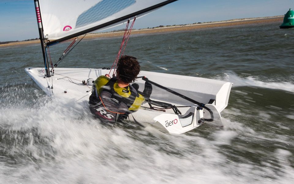 A man is sailing a small sailboat in the ocean.
