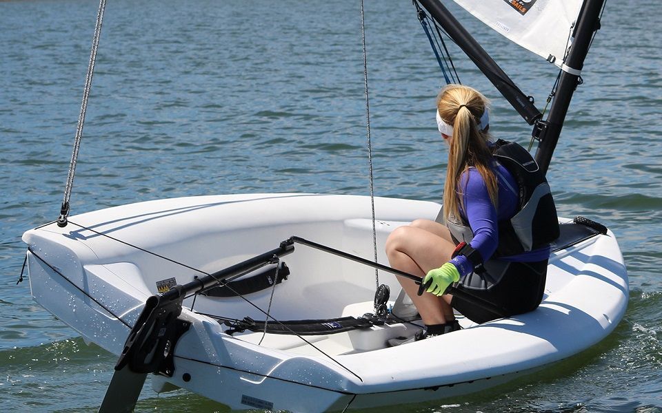 A woman is sitting on a small sailboat in the water.