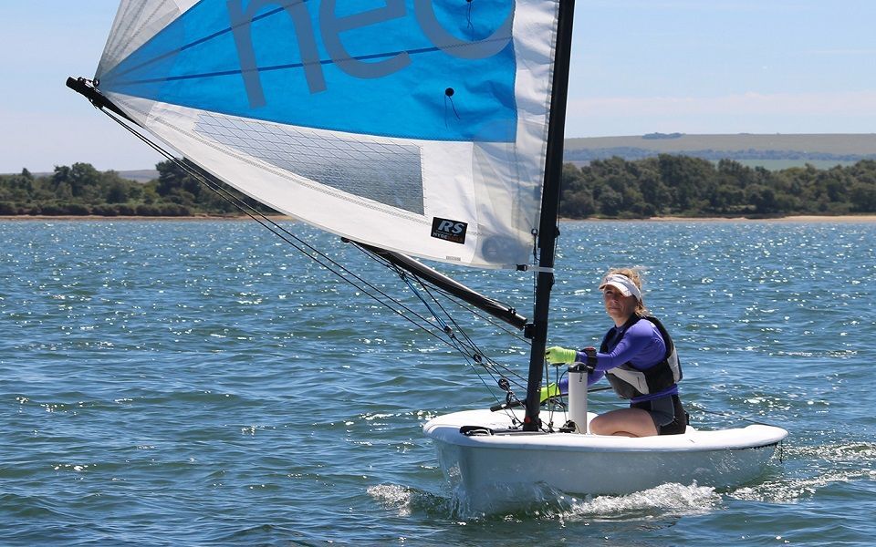 A woman is sailing a small sailboat on a lake.