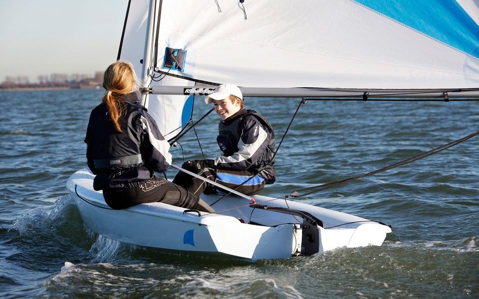 Two people are sailing a small boat in the water