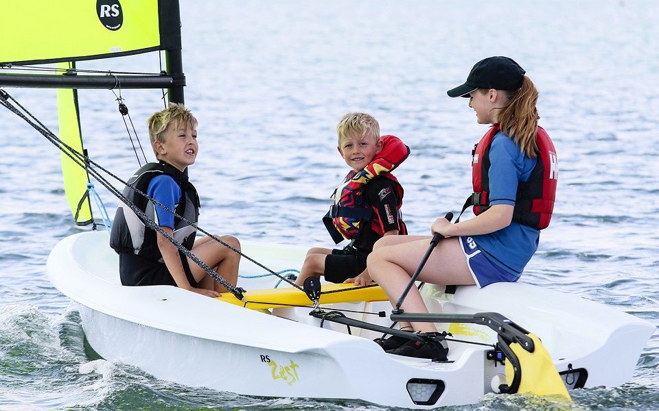 A group of people are sitting on a sailboat in the water.