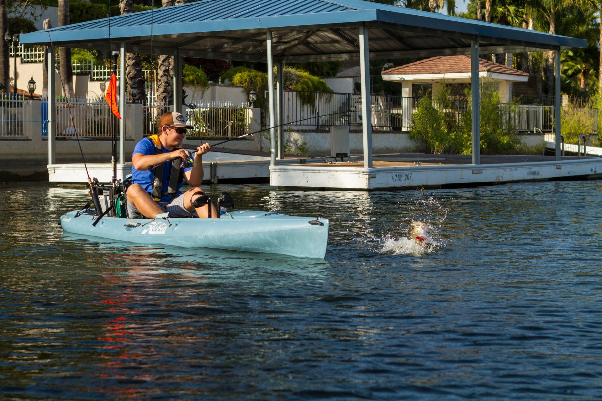 A man in a kayak is fishing with his dog
