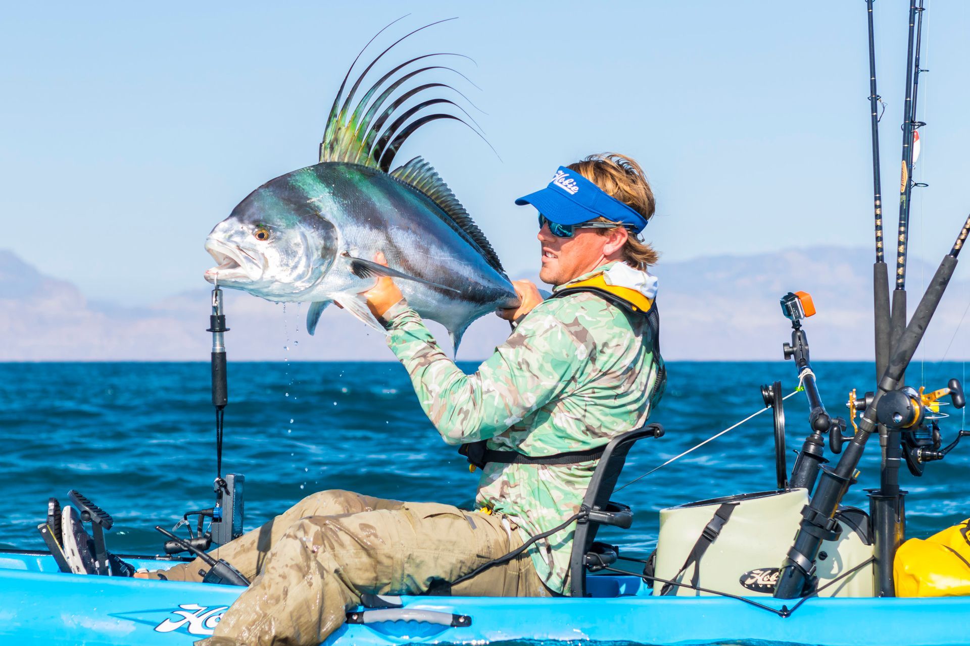 A woman is sitting in a kayak holding a large fish.