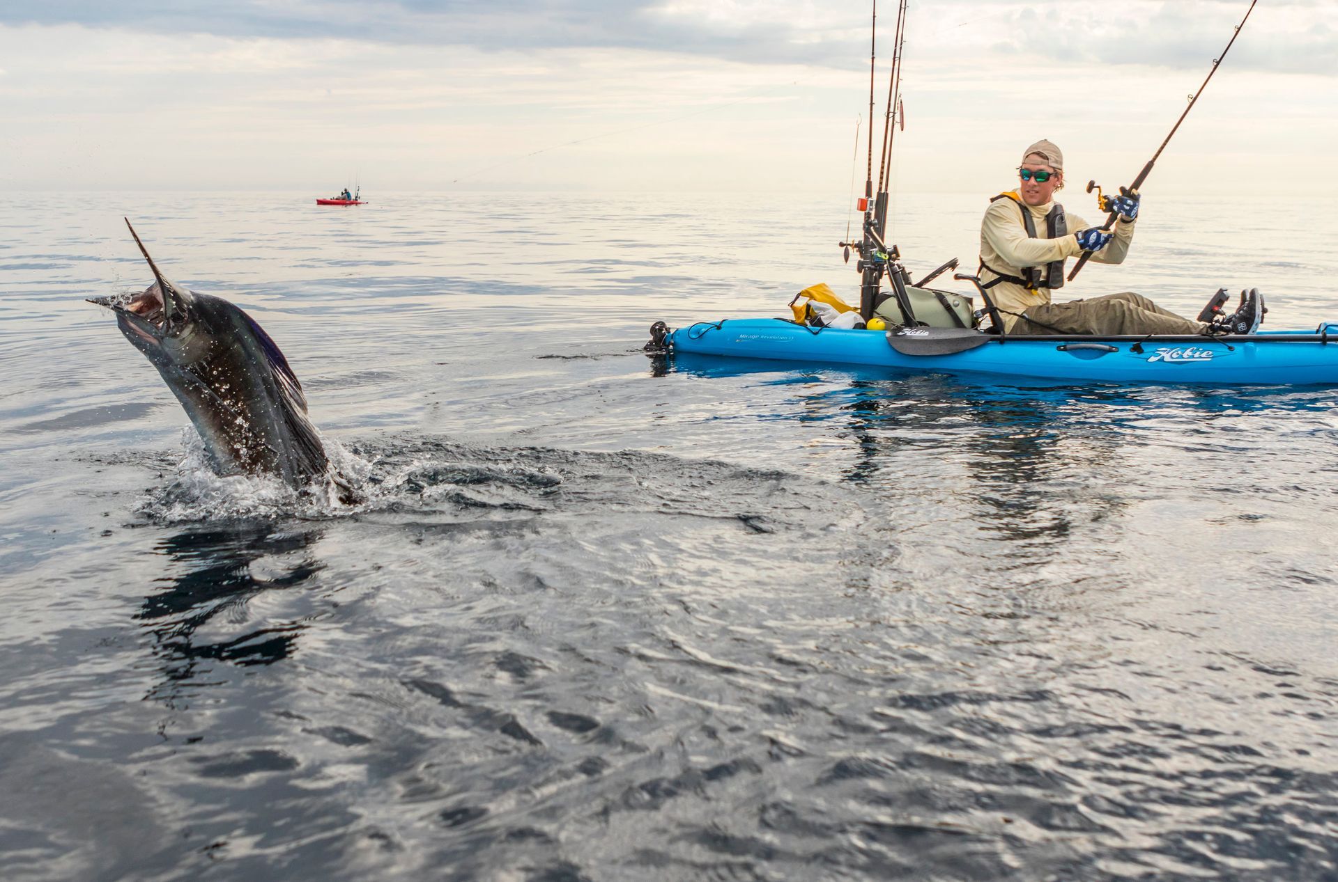 A man in a blue kayak is fishing in the ocean.