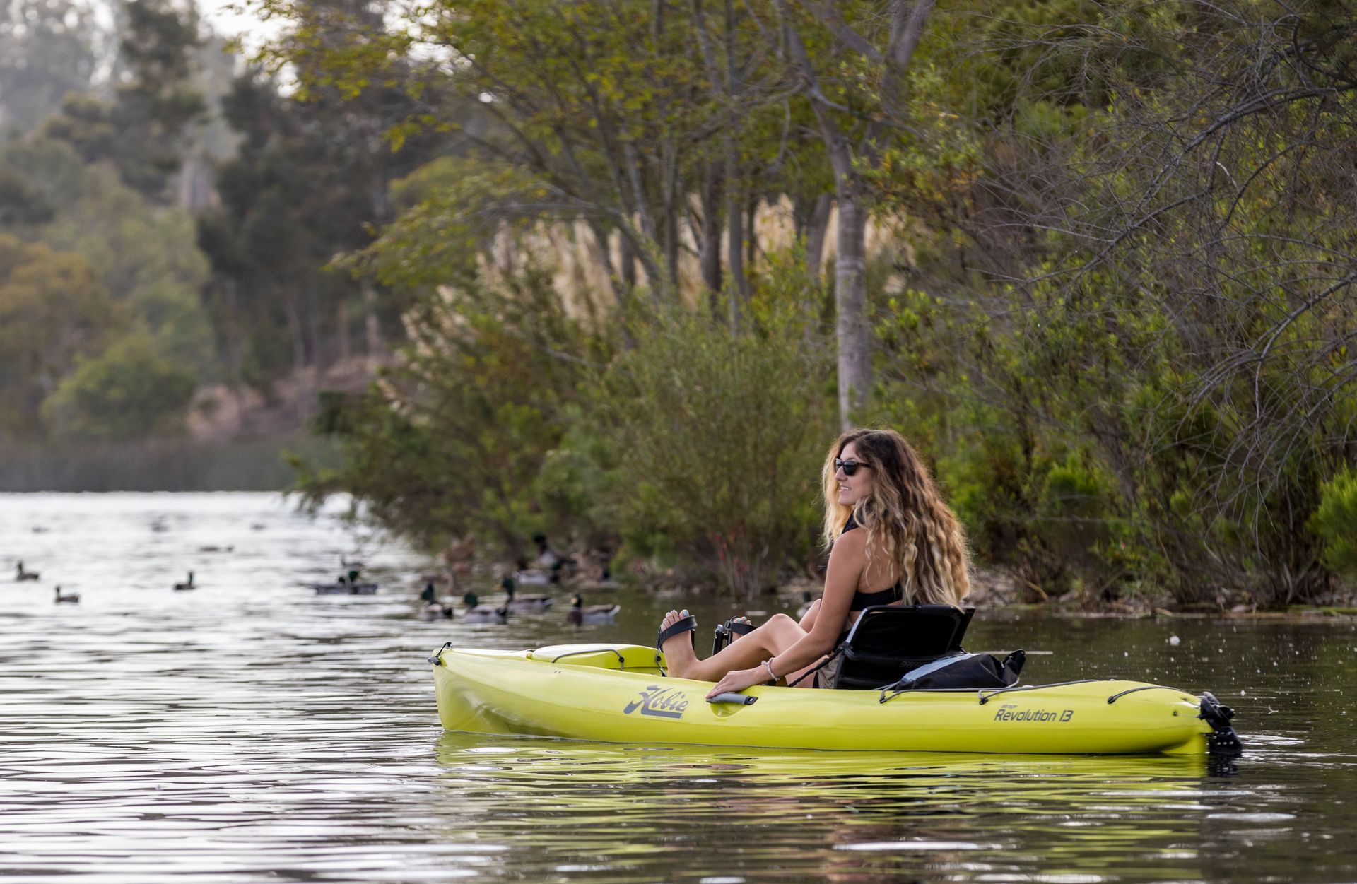 A woman is sitting in a yellow kayak on a lake.