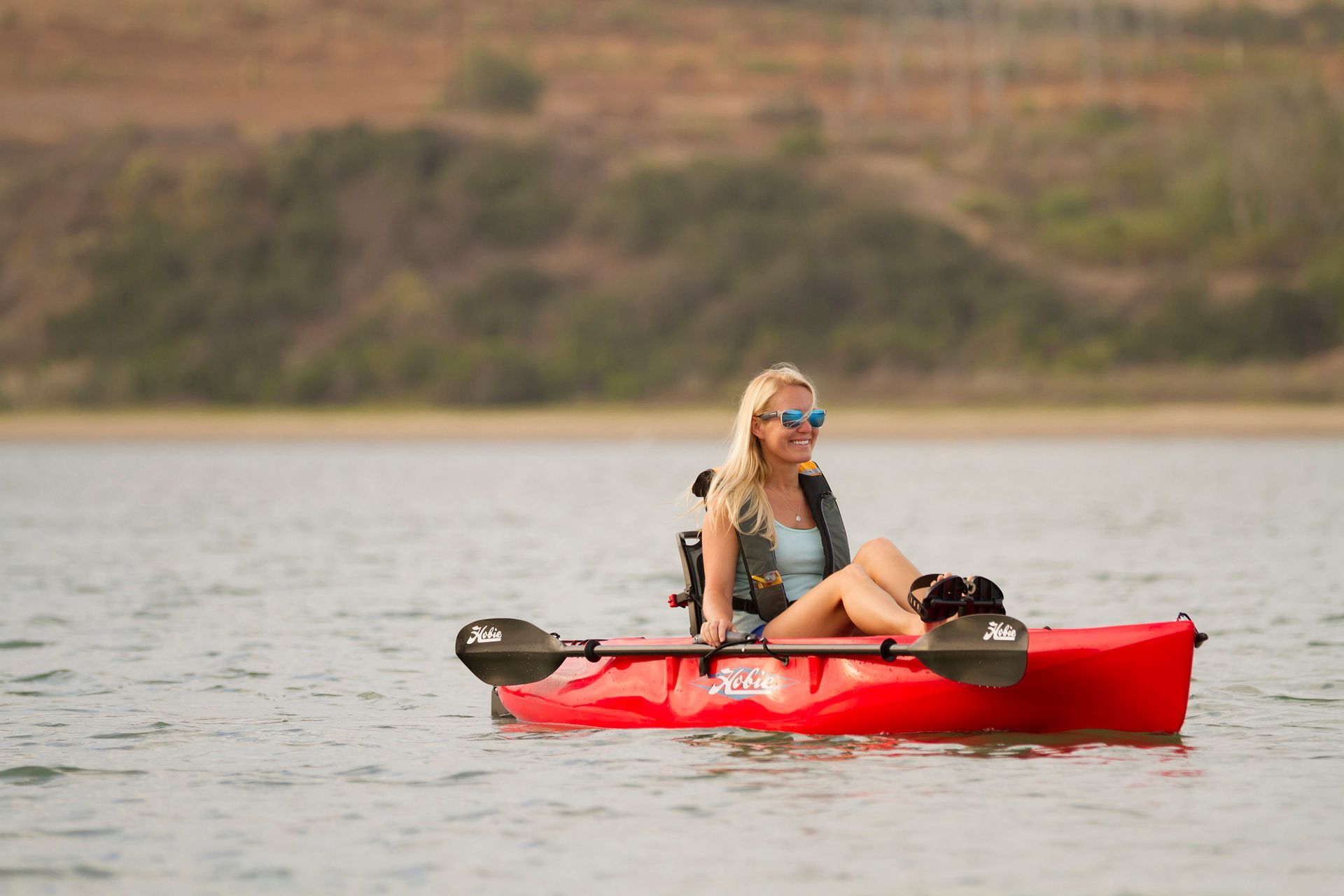 A woman is sitting in a red kayak on a lake.