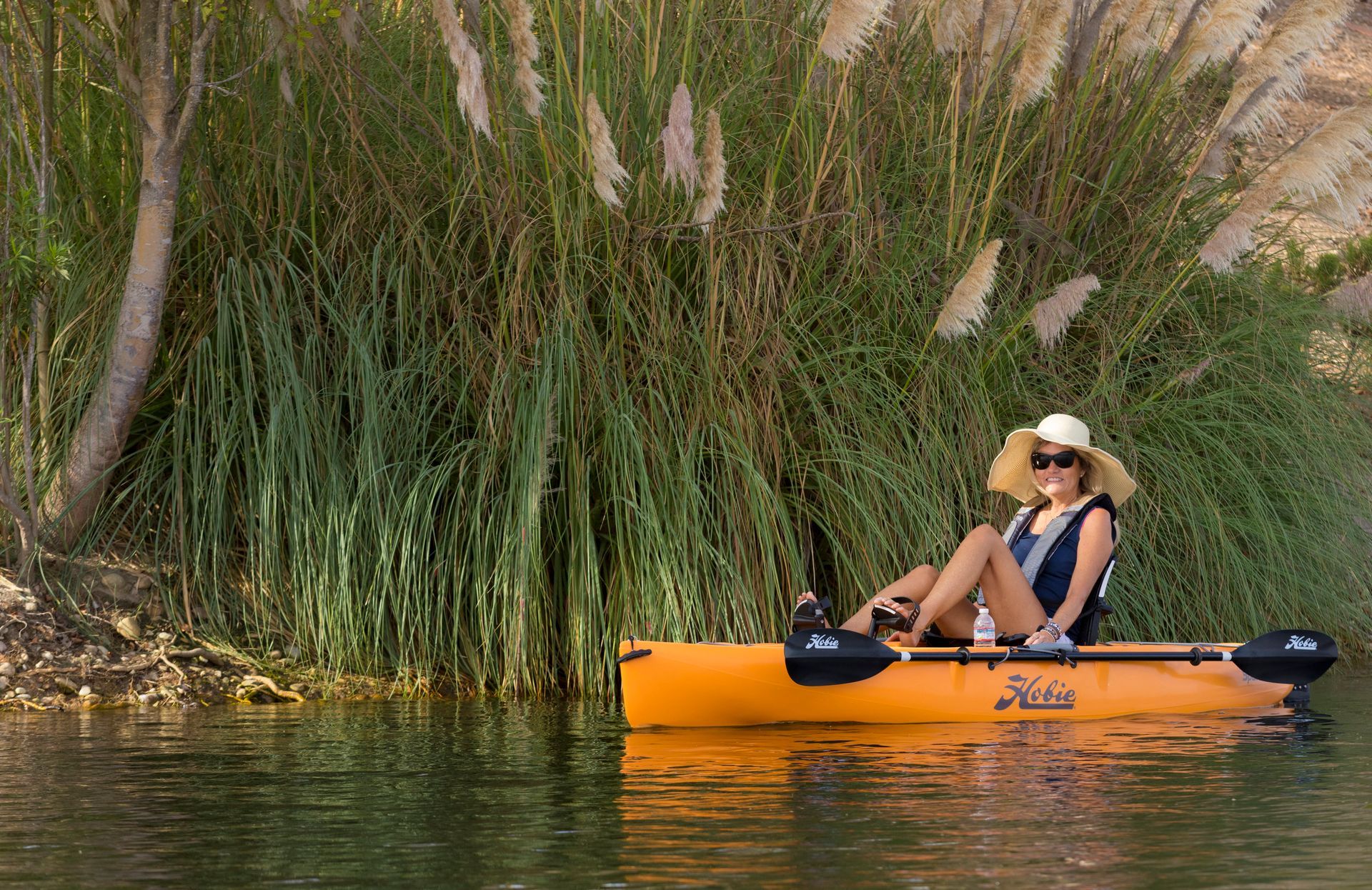 A woman is sitting in a yellow kayak on a river.