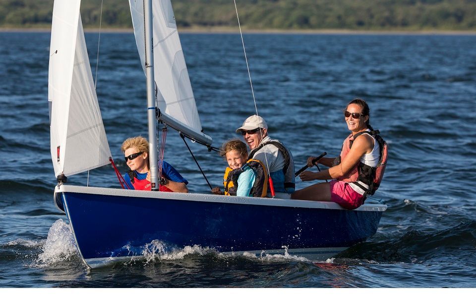 A group of people are sailing a small boat on a lake.