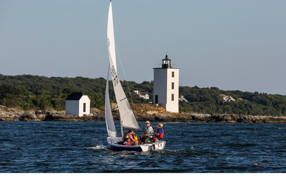 A sailboat with a lighthouse in the background