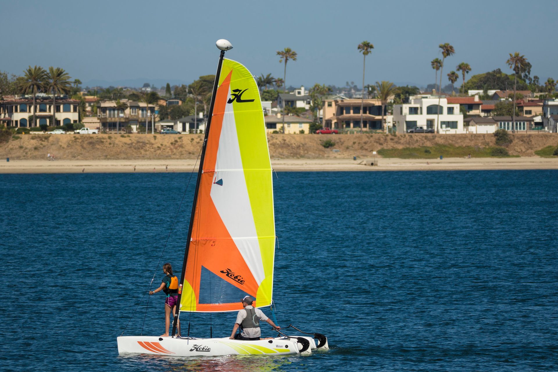 Two people are sailing a sailboat in the ocean.