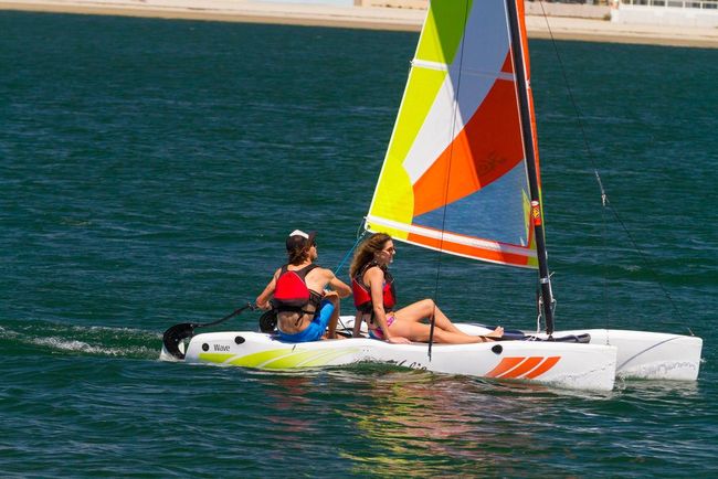 Two women are sitting on a sailboat in the water.