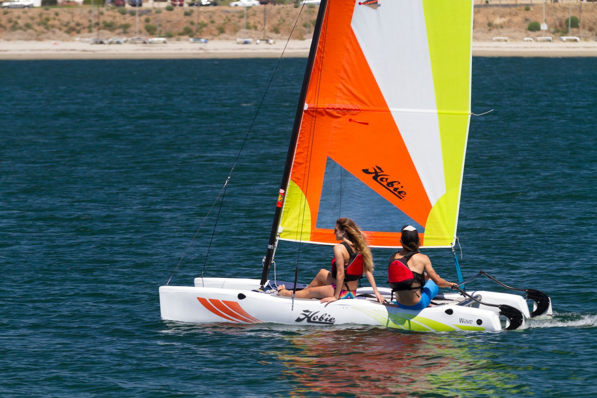 Two women are sailing a sailboat in the water