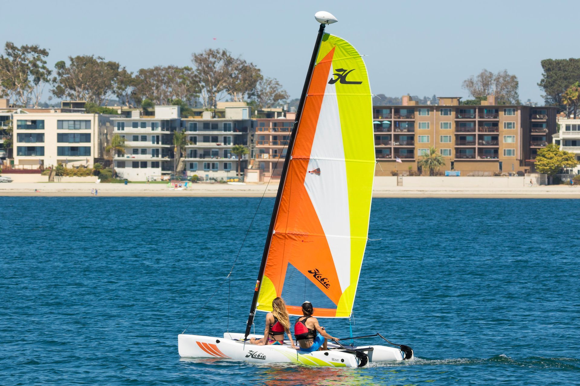 A couple of people are sailing a sailboat in the ocean.